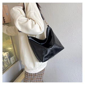 Close-up of black oily leather tote bag featuring a colorful patterned wide strap