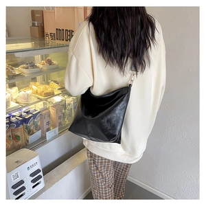 Minimalist black faux leather tote bag with a colorful bohemian wide shoulder strap