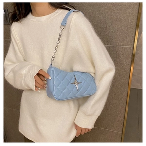 Detail of light blue quilted crossbody bag with silver star hardware and chain strap
