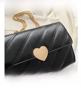 Detail of black crossbody bag with quilted stitching and gold heart-shaped metal buckle