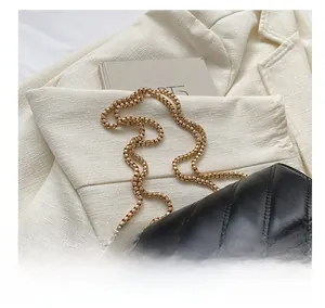 Macro detail of black quilted leather handbag with gold heart-shaped metal clasp and chain