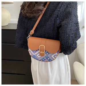 Ethnic style saddle bag with brown leather flap and colorful woven pattern shown on a model