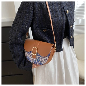 Close-up of vintage saddle bag with brown leather and colorful plaid knit stitching