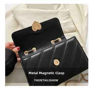 Close-up of black quilted bag with V-shaped stitching and golden magnetic buckle