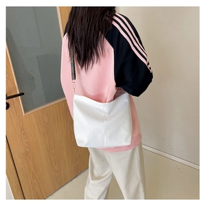 Detail of white leather crossbody bag featuring a branded monogram wide shoulder strap