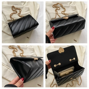 Detail of black quilted crossbody bag with golden heart lock and chic chain strap