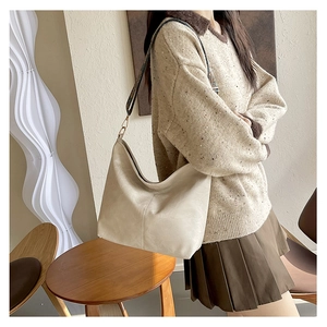 Minimalist beige hobo bag with vintage monogram strap shown on a model's shoulder