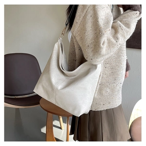 Detail of vintage textured white leather hobo bag with metallic ring on shoulder strap