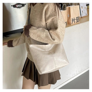 Detail of off-white tote bag featuring natural leather texture and jacquard shoulder strap