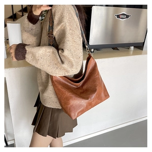 Detailed view of the brown oil-wax leather tote bag with a colorful embroidered strap