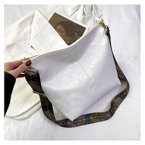 Close-up of white glossy tote bag featuring a colorful ethnic style woven shoulder strap