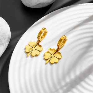 Elegant gold titanium steel clover drop earrings displayed on a white textured plate