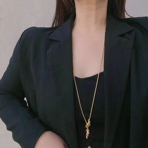 Long adjustable gold knot necklace with sleek snake chain worn on a black blazer