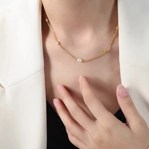 Elegant gold freshwater pearl necklace on model in white blazer for minimalist style