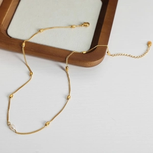 Elegant gold titanium steel necklace with small beads and a single freshwater pearl