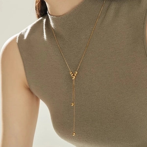 Minimalist gold Y-shaped long necklace with adjustable round beads on green sweater