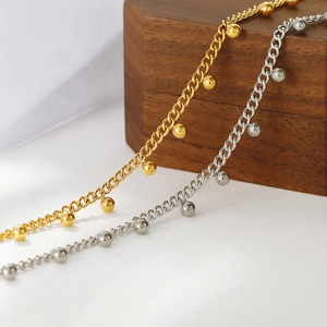 Colliers style français avec perles dorées et argentées sur fond bois sombre et blanc