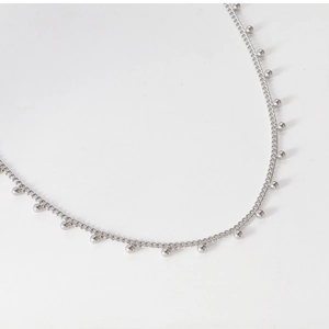Vue détaillée du collier à pendentifs boules argentées avec des perles minimalistes chic