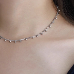 Collier minimaliste en argent avec petites perles polies sur une chaîne fine, porté par mannequin