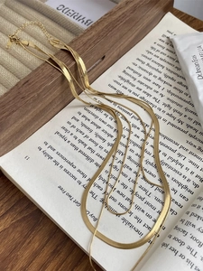 Collana a tre strati placcata oro 18K con catena a serpente su sfondo di un libro