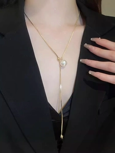Detail of adjustable gold-plated Y-necklace with elegant pearl pendant on dark blazer