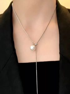 Silver Y-shaped snake chain necklace with pearl pendant on black blazer background