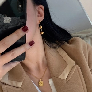 Polished gold celestial rectangle pendant necklace and triple ball dangle earrings on model
