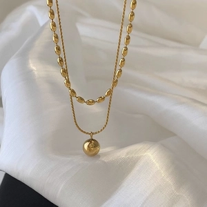 Double-layered 18K gold-plated necklace with polished sphere pendant on white silk fabric