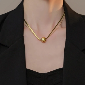 Double-layered gold ball pendant necklace featuring a snake chain and minimalist bead chain