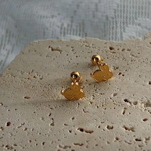 Golden rabbit stud earrings with luck engraving on textured stone background