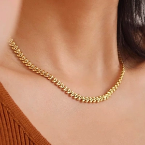 Golden wheat ear link necklace in titanium steel on model with brown knitwear