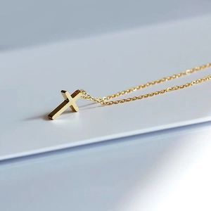 Minimalist 18k gold cross necklace with a polished pendant on a delicate O-chain