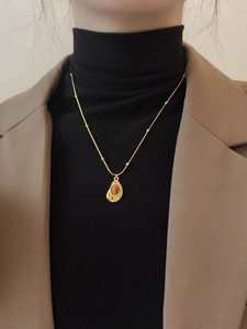 Détail du collier en œil de tigre avec perles dorées sur un pull noir élégant