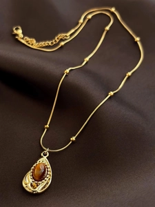 Collier vintage en or avec pendentif goutte en œil de tigre sur fond de soie marron