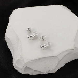 Minimalist silver teardrop stud earrings with a polished finish on textured stone