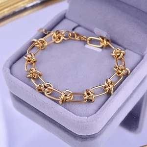 Golden titanium steel chain bracelet with knotted links on purple velvet jewelry box