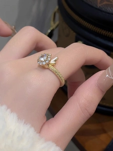 Détail d'une bague dorée rotative avec accents papillon et fleur en zircone