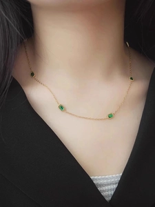 Collier élégant en titane doré avec zircons verts rectangulaires porté sur le décolleté
