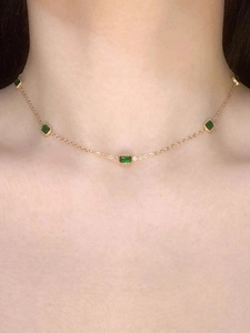 Collier en acier titane doré avec zircons émeraude porté par un mannequin en gros plan