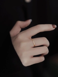 Primer plano de un anillo fino de acero titanio dorado con circonitas en la mano