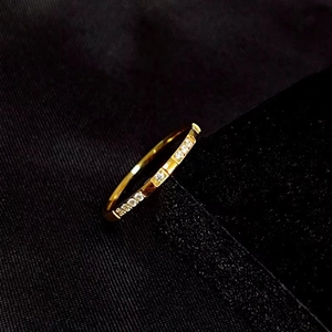 Minimalist gold titanium steel ring with sparkling crystals on black fabric background
