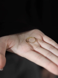 Anillo fino minimalista de acero de titanio dorado con circonitas sobre la palma