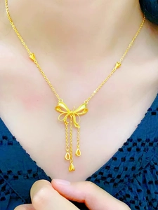 Collier nœud doré élégant avec pampilles et breloques cœur sur un mannequin femme