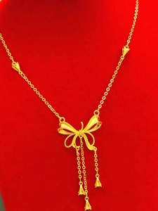 Collier nœud doré élégant avec chaînes à glands sur fond de velours rouge