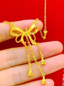 Élégant collier nœud doré avec pendentifs à glands sur fond de velours rouge