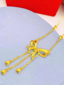 Collier nœud doré avec pampilles et pendentifs en forme de cloche sur fond bleu clair