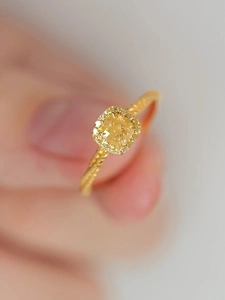 Détail macro d'une bague cristal jaune avec sertissage halo et anneau torsadé élégant