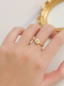 Détail d'une bague avec cristal jaune carré et anneau doré torsadé porté à la main
