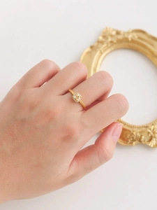 Détail d'une bague jaune taille coussin avec halo de diamants et anneau torsadé doré