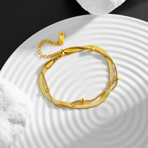 Double-layered gold titanium steel anklet with snake chain and beads on white ceramic